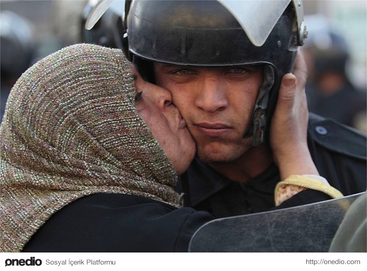 Mısırlı bir kadın, göstericilere ateş etmeyi reddeden bir polisi öperken.